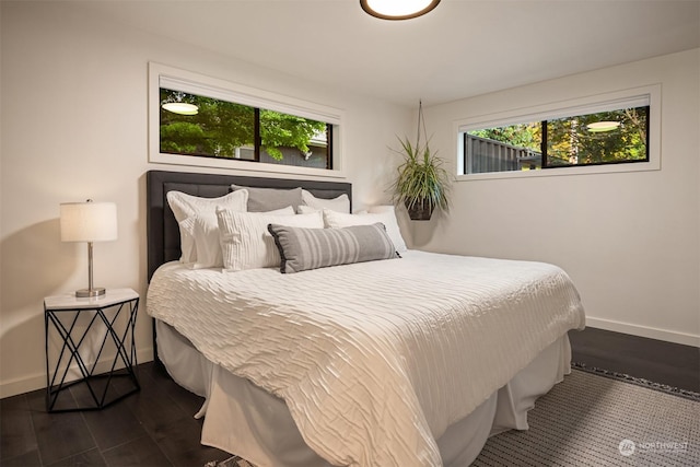 bedroom with multiple windows and dark hardwood / wood-style flooring