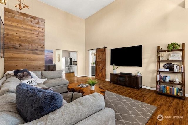 living room with dark hardwood / wood-style flooring, a barn door, and a high ceiling