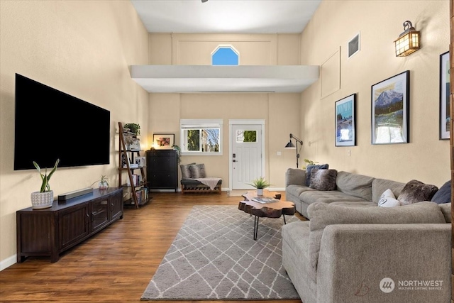 living room with a towering ceiling and dark hardwood / wood-style floors