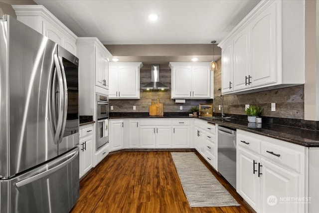 kitchen with white cabinetry, appliances with stainless steel finishes, sink, and wall chimney range hood