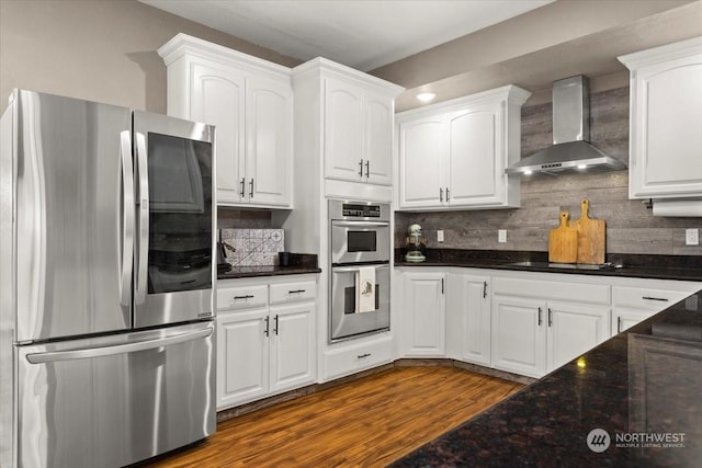 kitchen featuring appliances with stainless steel finishes, dark wood-type flooring, white cabinets, and wall chimney exhaust hood