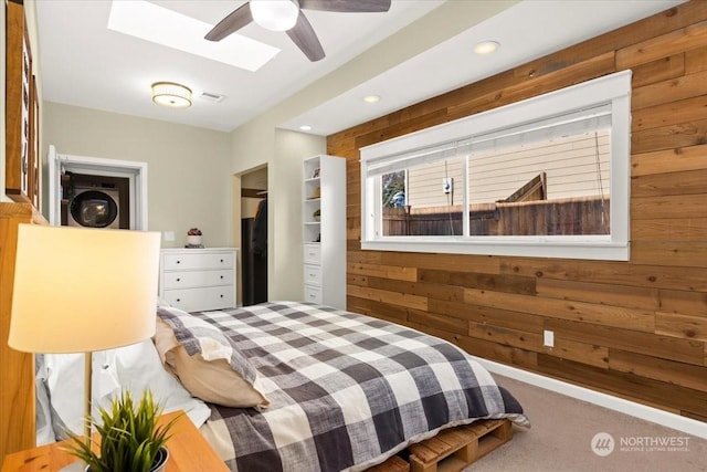 carpeted bedroom featuring wooden walls and a skylight