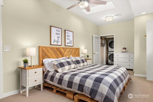 bedroom featuring stacked washer / drying machine, light carpet, and a skylight