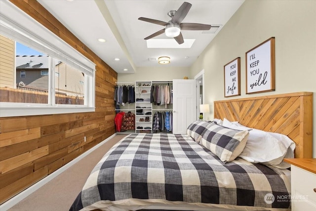 carpeted bedroom with wooden walls, a closet, and ceiling fan