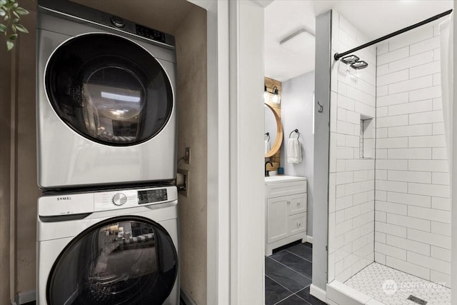 washroom featuring stacked washing maching and dryer, sink, and dark tile patterned flooring