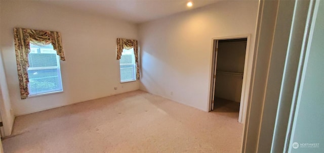 unfurnished bedroom with multiple windows, a walk in closet, and carpet flooring