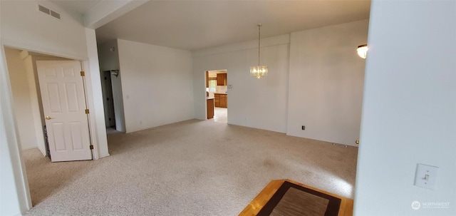 carpeted empty room featuring a chandelier