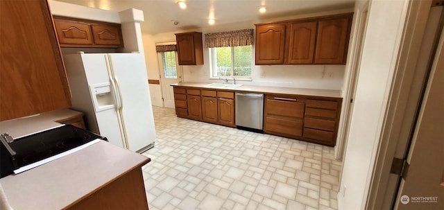 kitchen with stainless steel dishwasher, white refrigerator with ice dispenser, and sink