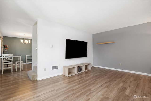 unfurnished living room featuring an inviting chandelier and hardwood / wood-style flooring