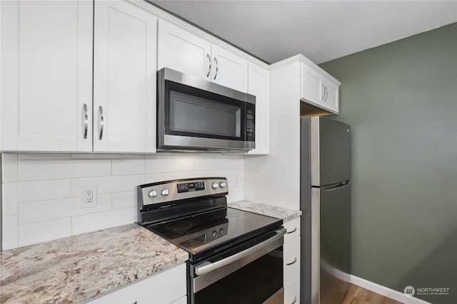 kitchen with decorative backsplash, light stone countertops, white cabinets, and appliances with stainless steel finishes