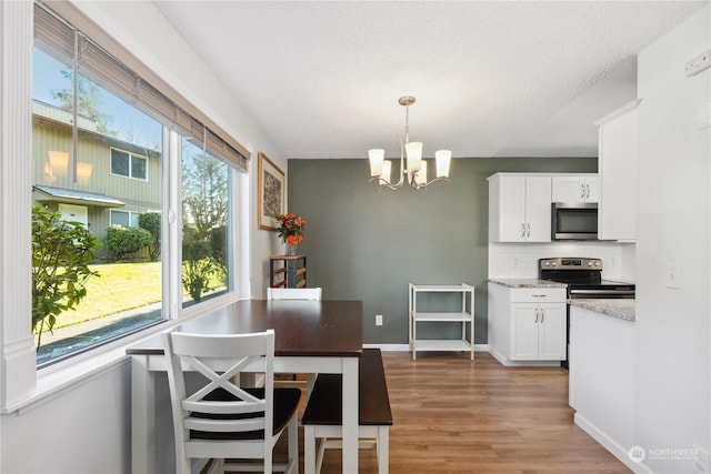 kitchen with white cabinetry, light stone counters, pendant lighting, and appliances with stainless steel finishes