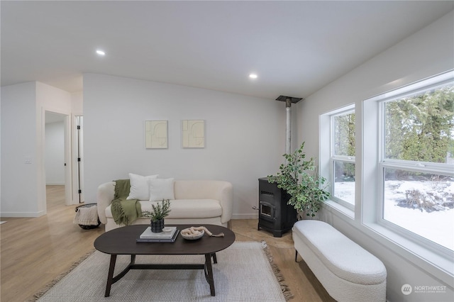 living room with light hardwood / wood-style flooring, vaulted ceiling, and a wood stove