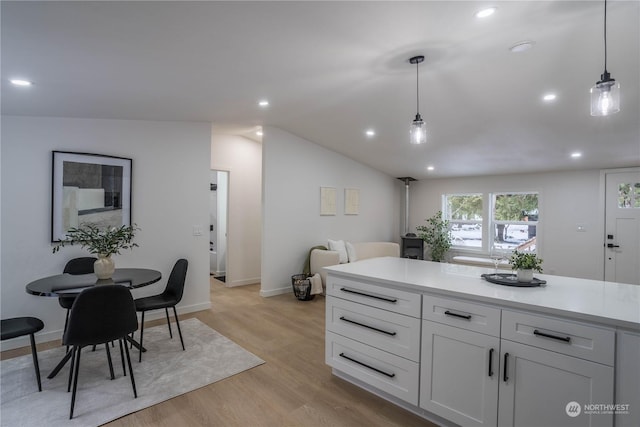 kitchen with white cabinetry, decorative light fixtures, light hardwood / wood-style flooring, and lofted ceiling