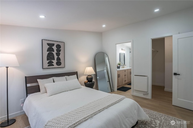 bedroom with a walk in closet, connected bathroom, and light hardwood / wood-style floors