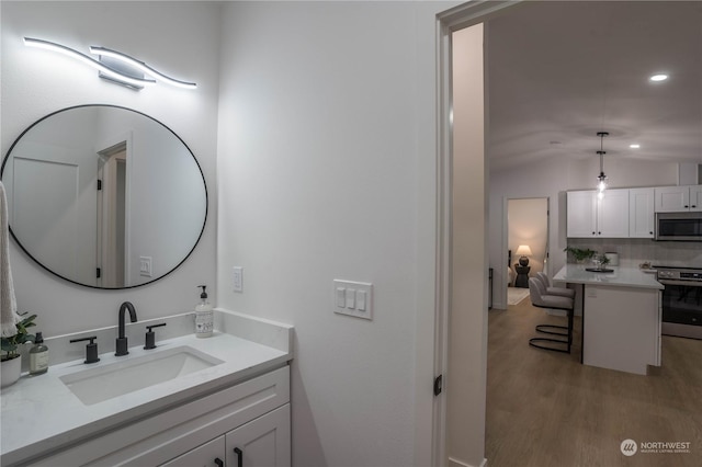 bathroom with lofted ceiling, backsplash, hardwood / wood-style flooring, and vanity