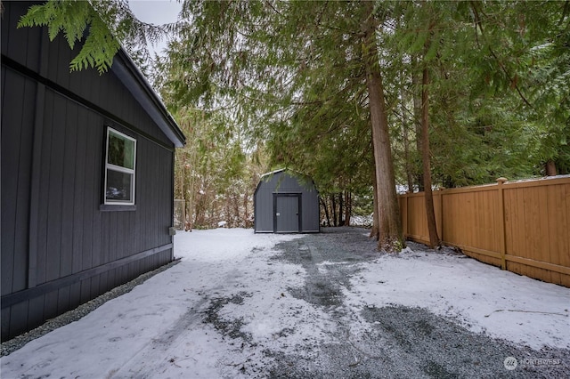 yard layered in snow featuring a storage shed