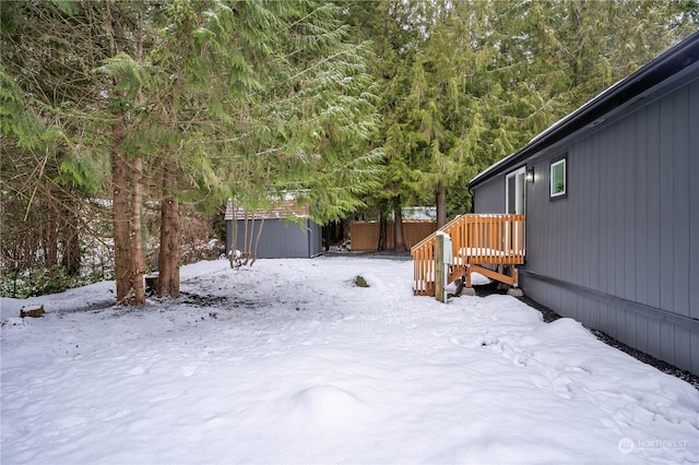 yard covered in snow featuring a storage shed and a deck