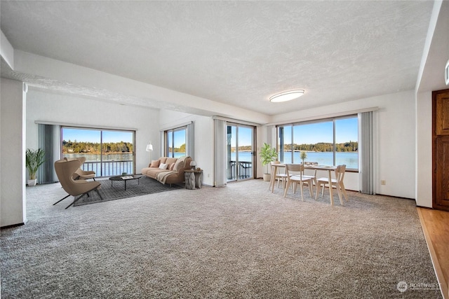 unfurnished living room with a water view, light colored carpet, and a textured ceiling