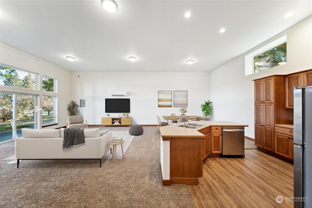 kitchen featuring appliances with stainless steel finishes, a kitchen island with sink, sink, and light wood-type flooring