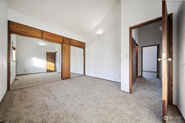 unfurnished bedroom with light colored carpet and high vaulted ceiling