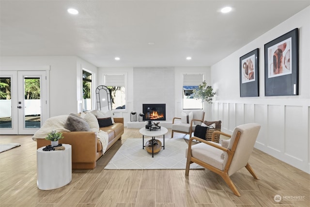 living room featuring a large fireplace, light hardwood / wood-style flooring, and french doors