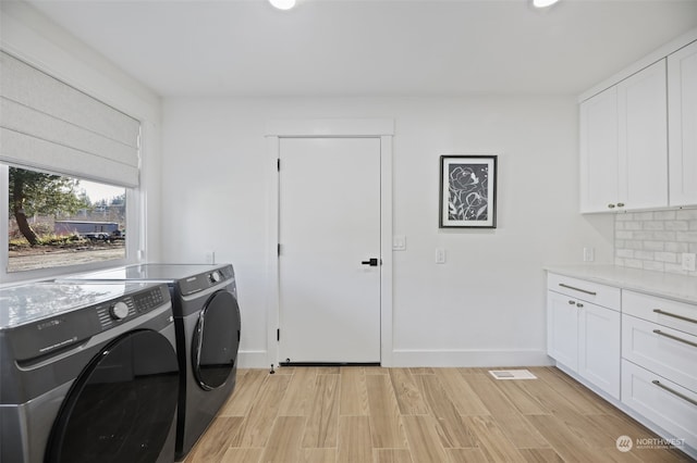 laundry area with cabinets, separate washer and dryer, and light wood-type flooring