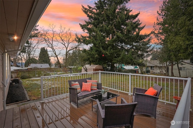 deck at dusk with a yard, an outdoor hangout area, and a shed