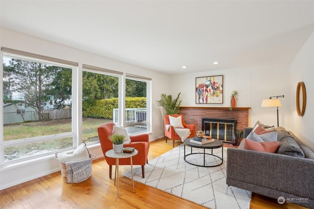 living room with a brick fireplace and light hardwood / wood-style flooring