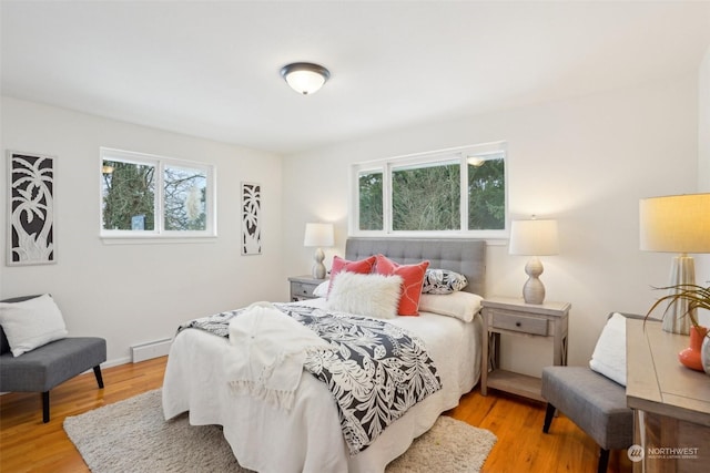 bedroom with baseboard heating and light wood-type flooring