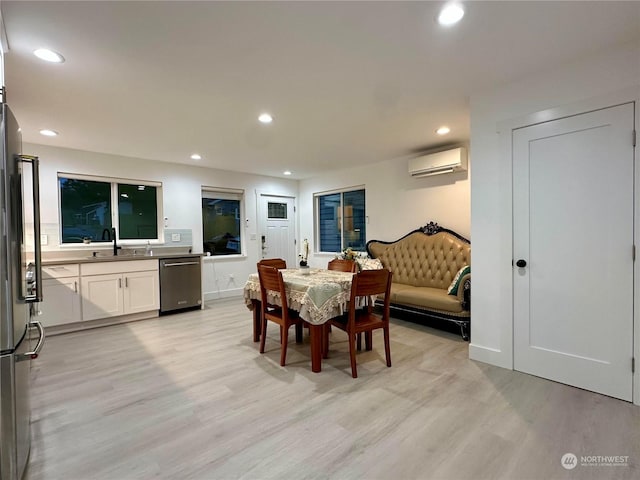 dining space featuring an AC wall unit, sink, and light hardwood / wood-style floors