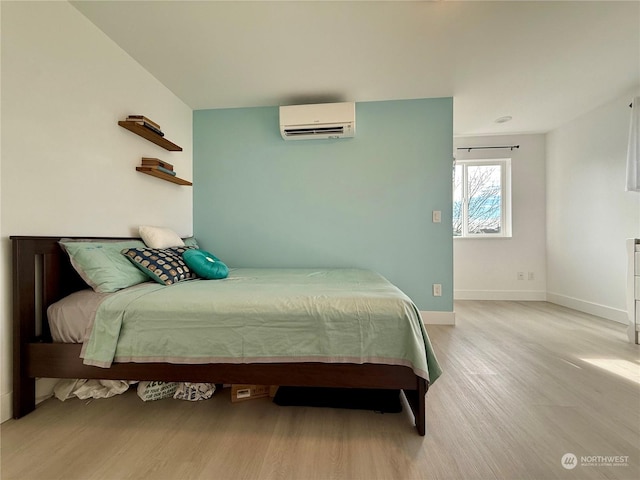 bedroom featuring light hardwood / wood-style flooring and a wall mounted AC