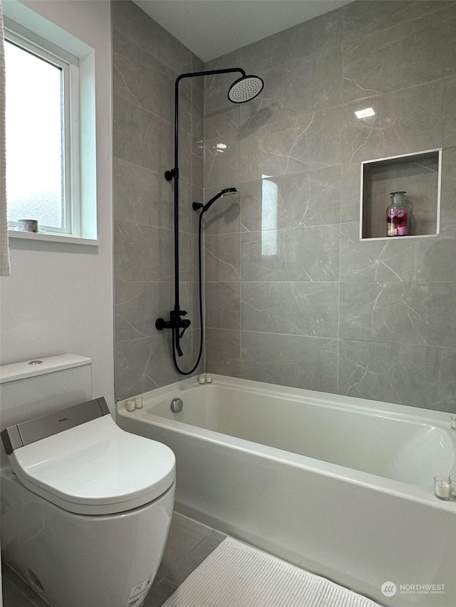 bathroom with tiled shower / bath combo and toilet