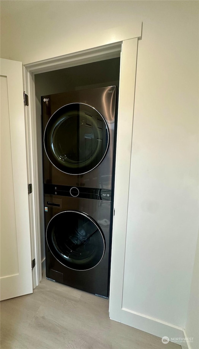 laundry area featuring stacked washer / drying machine and light hardwood / wood-style floors