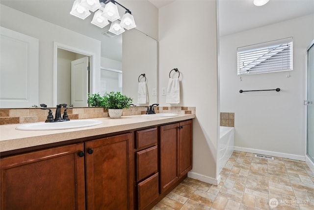 bathroom featuring stone finish floor, a garden tub, a sink, and double vanity