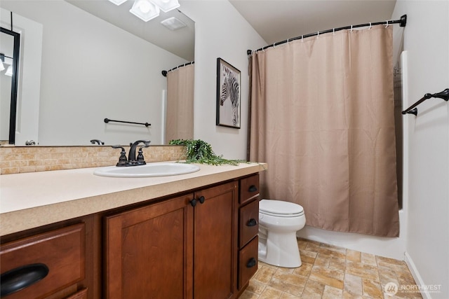 bathroom with decorative backsplash, toilet, shower / bath combo, stone finish flooring, and vanity