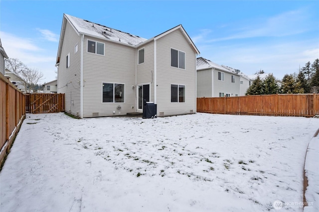 snow covered house featuring a fenced backyard