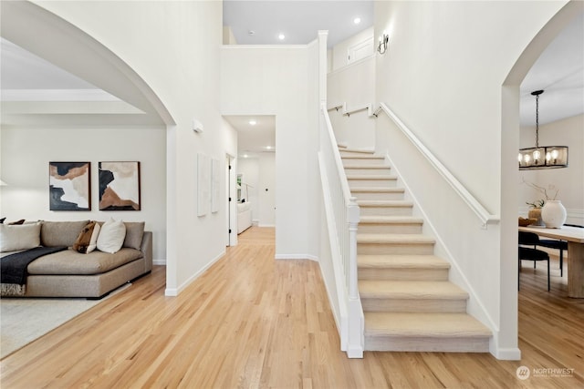 interior space with crown molding, wood-type flooring, a chandelier, and a high ceiling