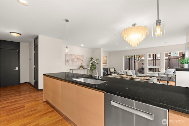 kitchen with dishwasher, open floor plan, hanging light fixtures, light wood-style floors, and a sink