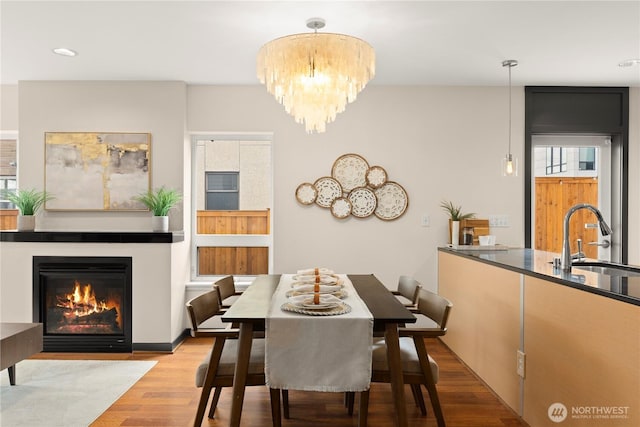 dining room featuring a fireplace with flush hearth, wood finished floors, and an inviting chandelier