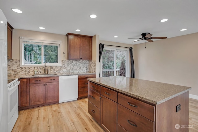 kitchen with sink, white appliances, plenty of natural light, a center island, and light hardwood / wood-style floors