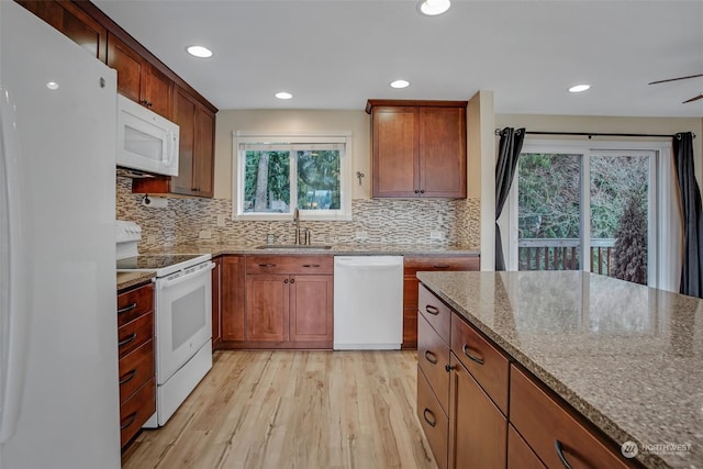 kitchen with sink, white appliances, light stone counters, tasteful backsplash, and light hardwood / wood-style floors