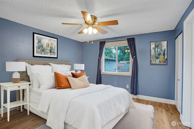 bedroom with ceiling fan, a textured ceiling, light wood-type flooring, and a closet