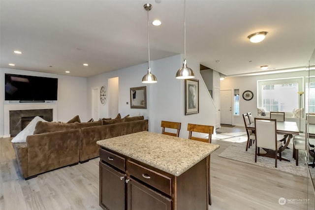 kitchen featuring a premium fireplace, light hardwood / wood-style flooring, dark brown cabinetry, and decorative light fixtures