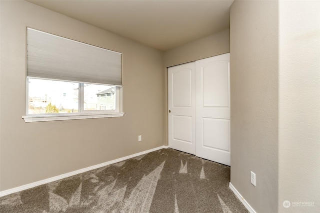 unfurnished bedroom with dark colored carpet and a closet