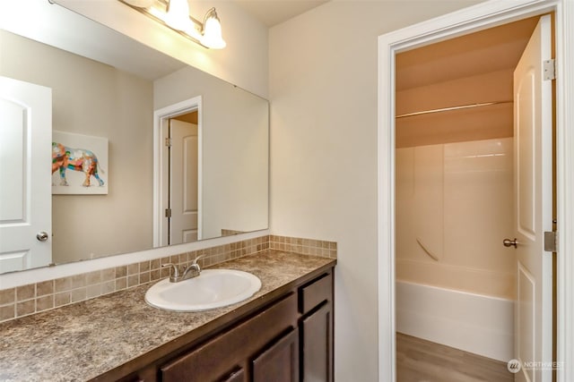 bathroom featuring shower / bath combination, vanity, and backsplash