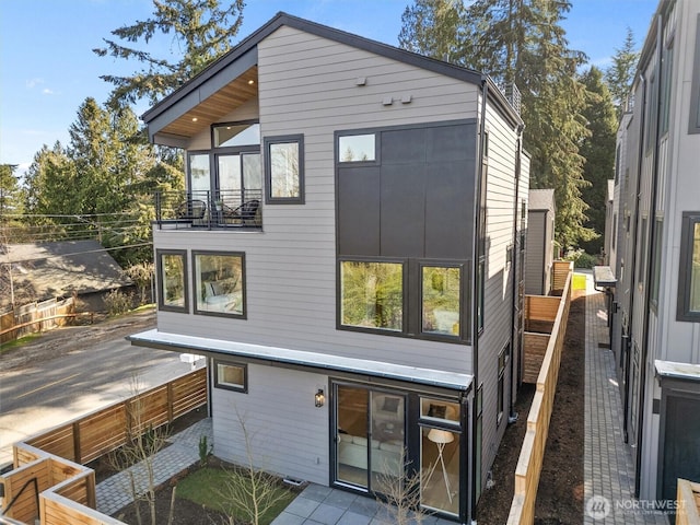 rear view of house featuring fence and a balcony