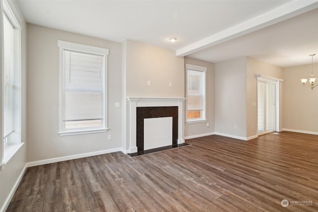 unfurnished living room with a healthy amount of sunlight, dark wood-type flooring, and a chandelier