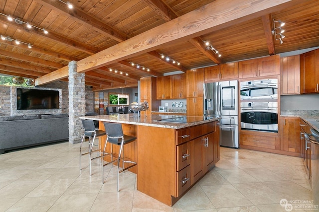 kitchen featuring a kitchen island, beamed ceiling, stainless steel appliances, light stone countertops, and wooden ceiling