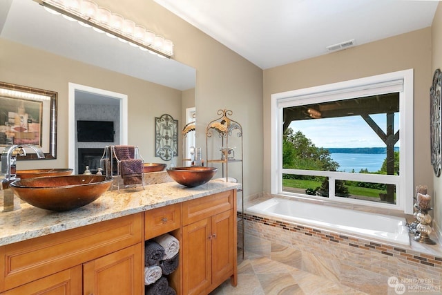 bathroom featuring vanity, tiled tub, and a water view