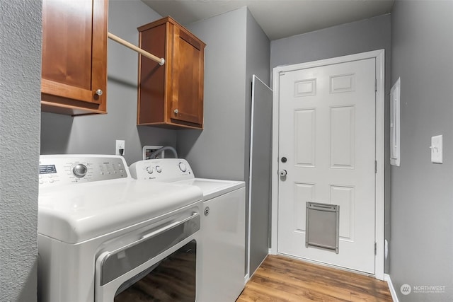 laundry area with cabinets, washer and dryer, and light hardwood / wood-style floors